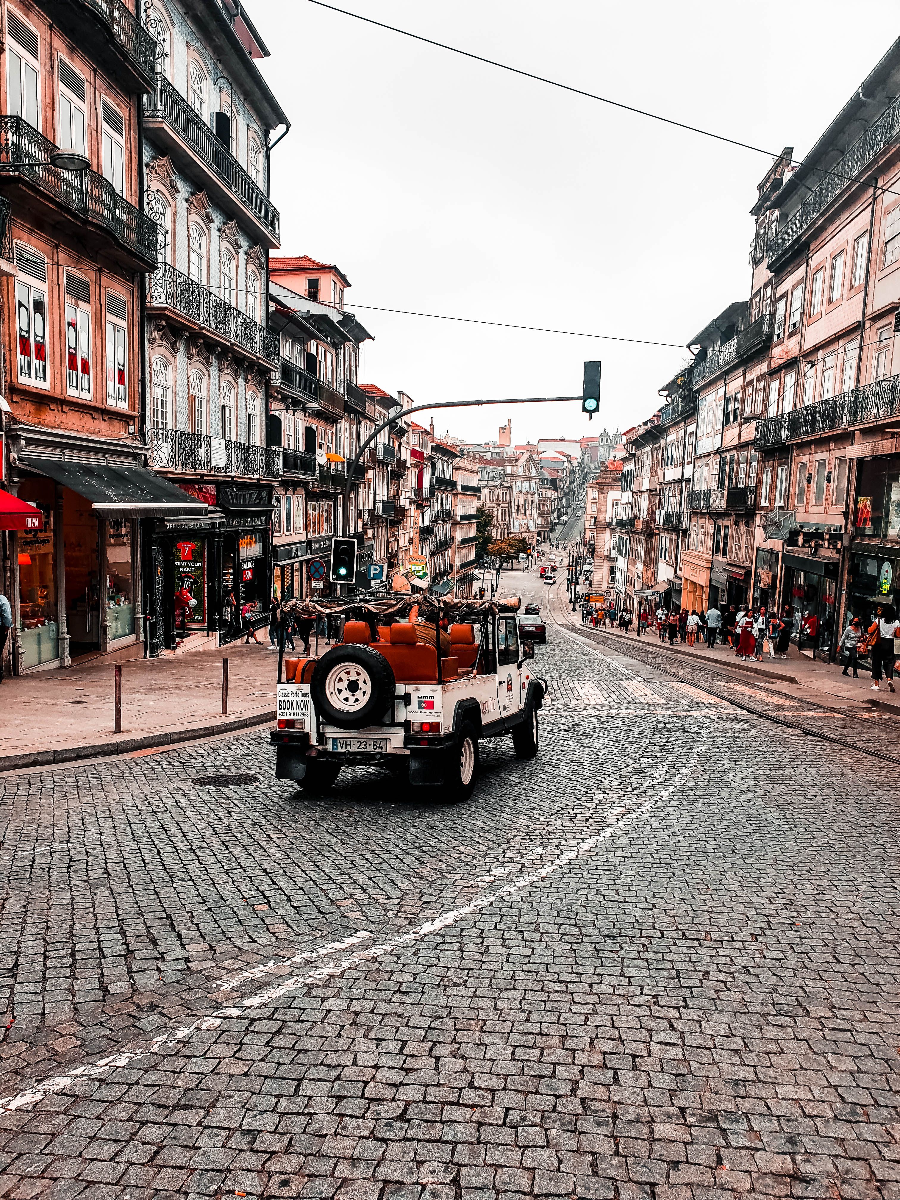 Cars on a Cobblestone Street between Buildings at Sunset · Free Stock Photo