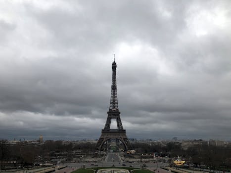 Aerial view of the Eiffel Tower under a cloudy sky in Paris, capturing its iconic structure.