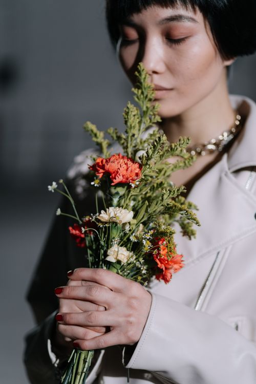 Free Close-up of a serene woman holding a fresh flower bouquet indoors. Stock Photo