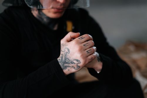 Free Close-up of tattooed hands clasped in a thoughtful pose, conveying introspection and contemplation. Stock Photo