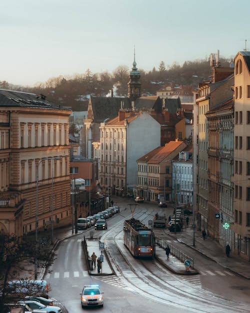 An Aerial Photography of a Tram and Cars on the Road Between Buildings