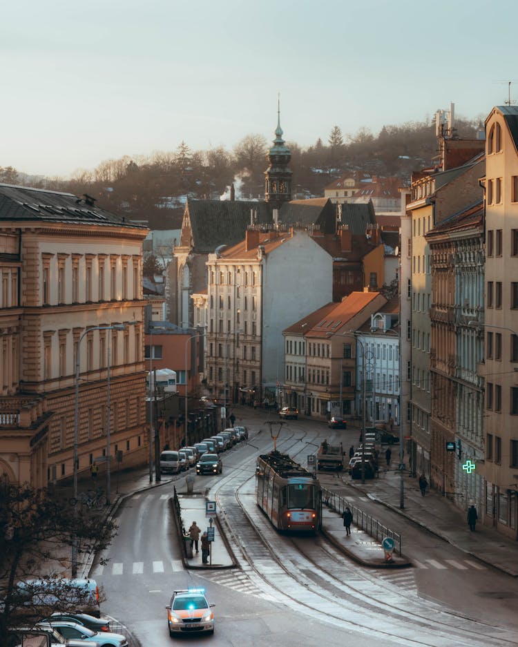 An Aerial Photography Of A Tram And Cars On The Road Between Buildings