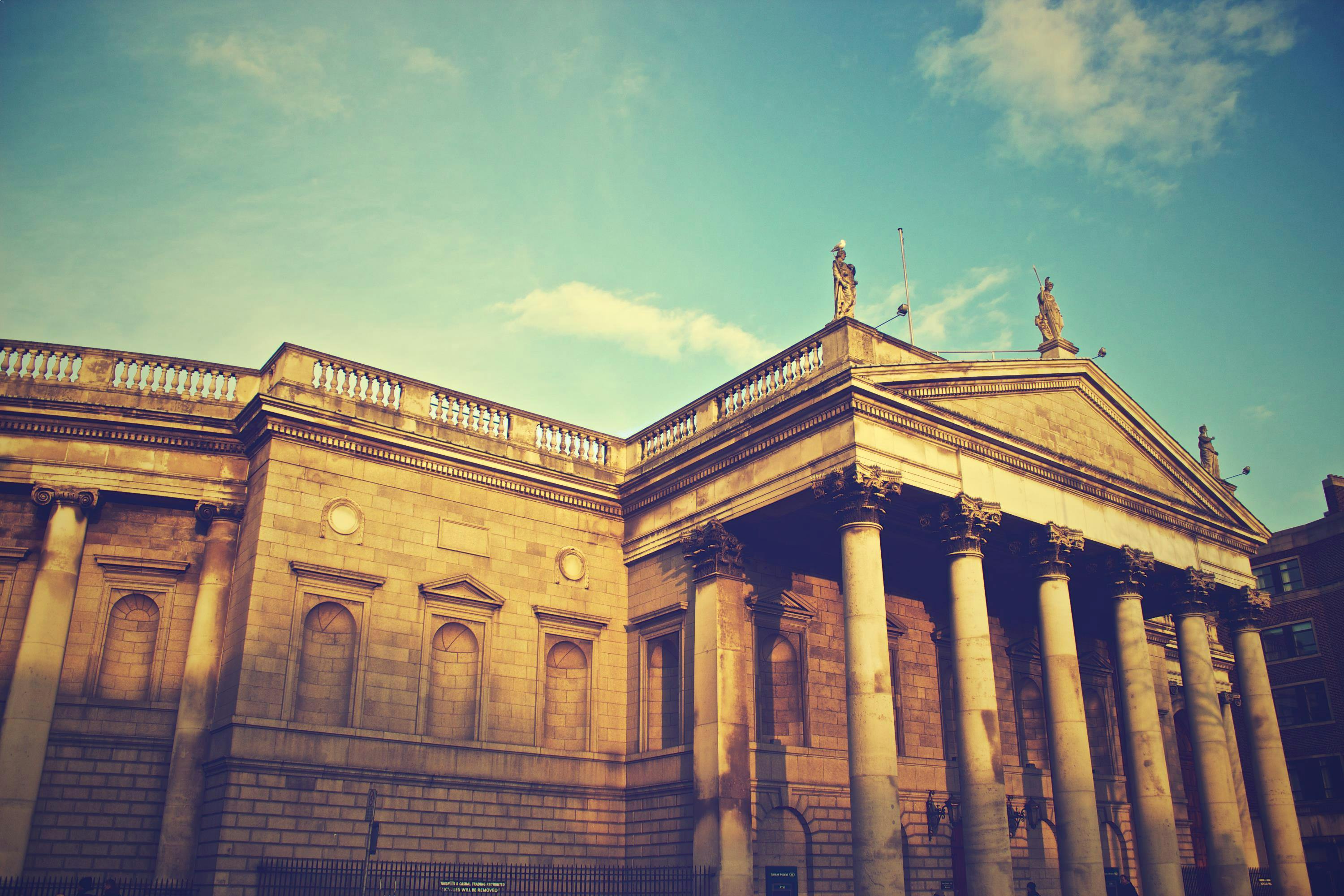 Free A vintage-styled photo of a historical building with classical architecture and columns under a clear sky. Stock Photo