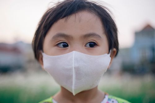 Free Close-up of a young child wearing a face mask outdoors, highlighting health and protection. Stock Photo