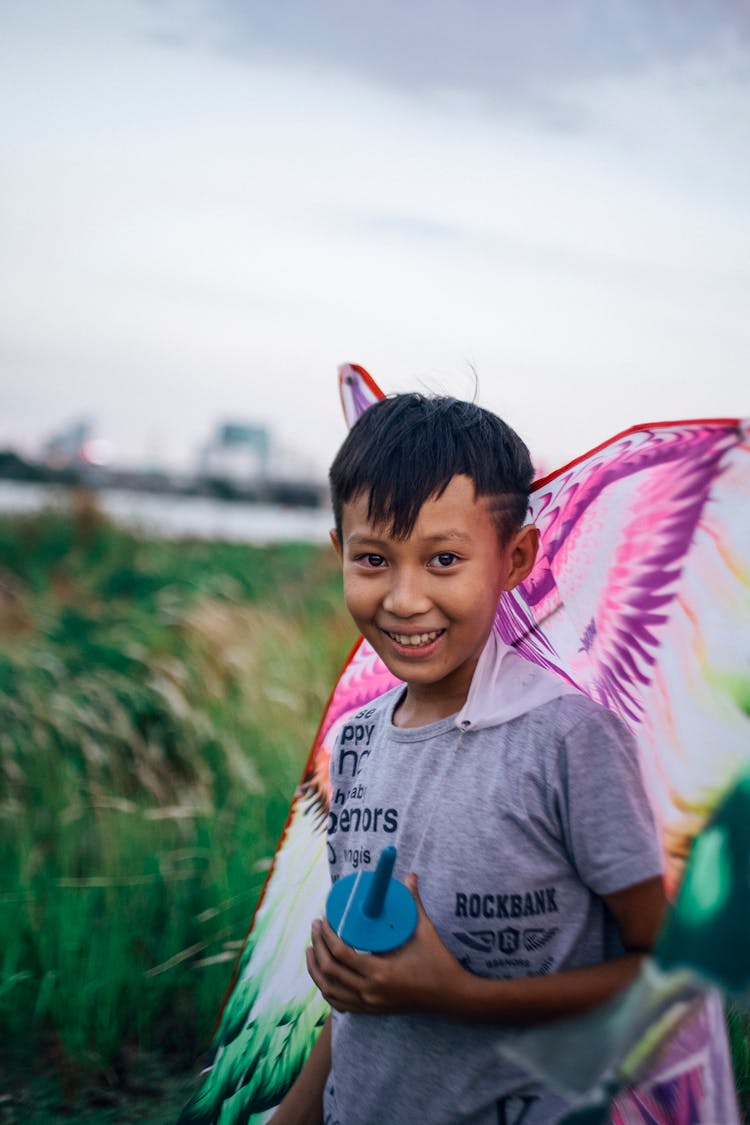 Portrait Of A Boy In Field With A Colourful Kite