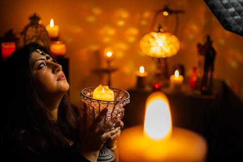 Woman Holding a Burning Candle and Looking Up 