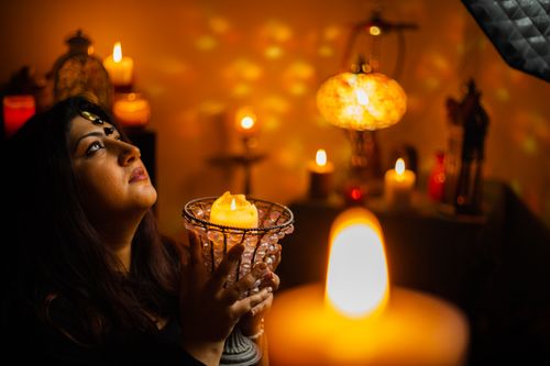 Free A woman holding a glowing candle in a mystical setting, engulfed in candlelight and spirituality. Stock Photo