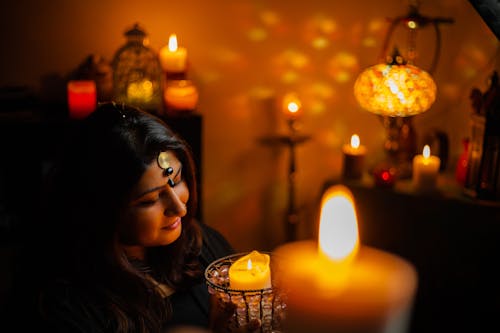 Woman Holding a Burning Candle in a Room Full of Candles 