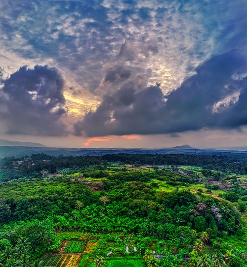 Free Stunning aerial photo of lush green countryside and dramatic clouds at sunset in Banten, Indonesia. Stock Photo