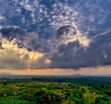 Aerial view of lush countryside with dramatic clouds during sunset in Banten, Indonesia.
