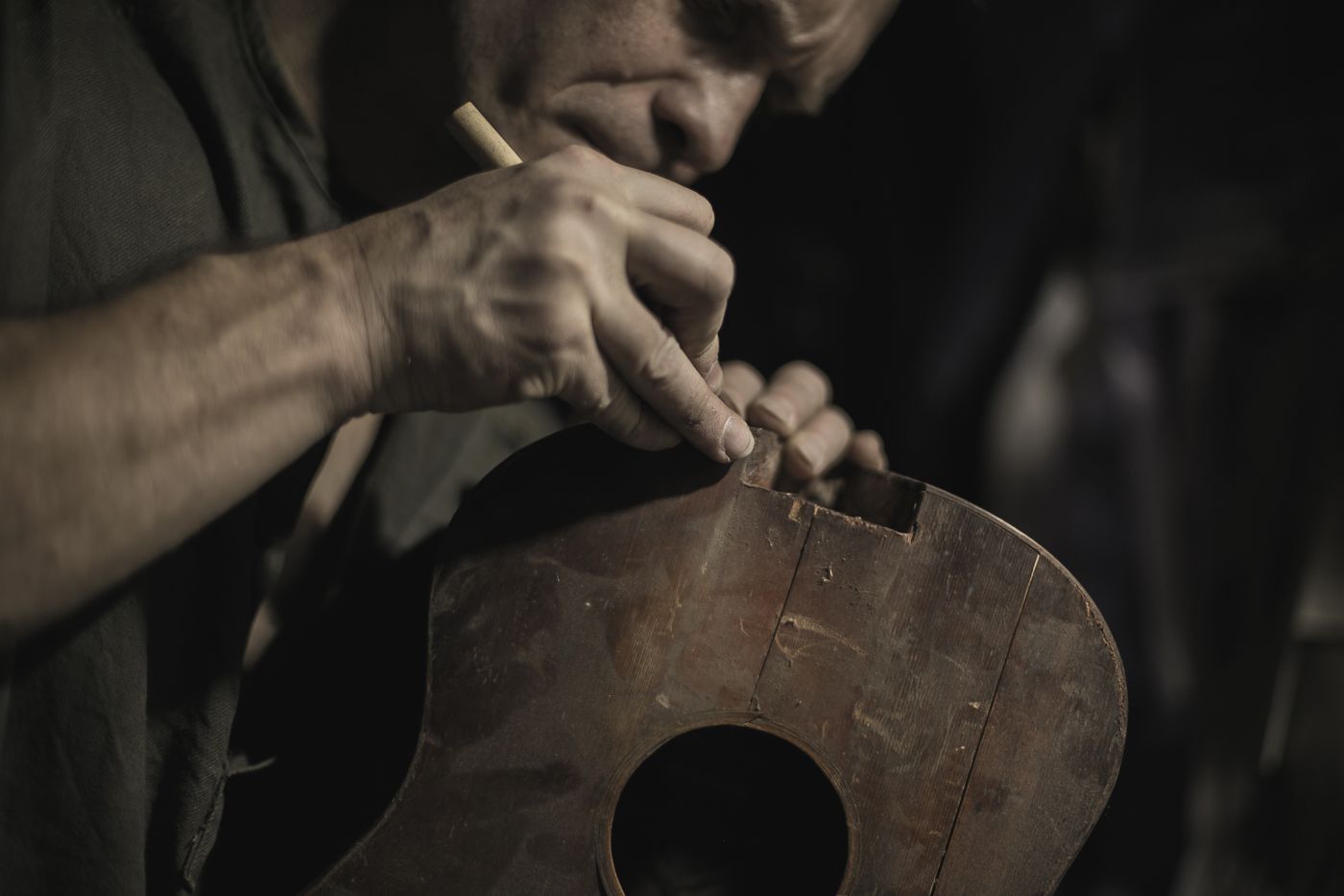 A luthier working on an acoustic guitar in a workshop