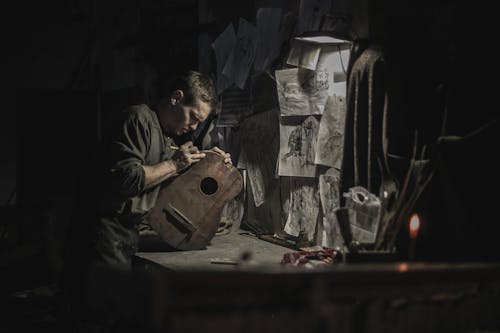 Man in Black Button-Up Shirt Carving a Guitar