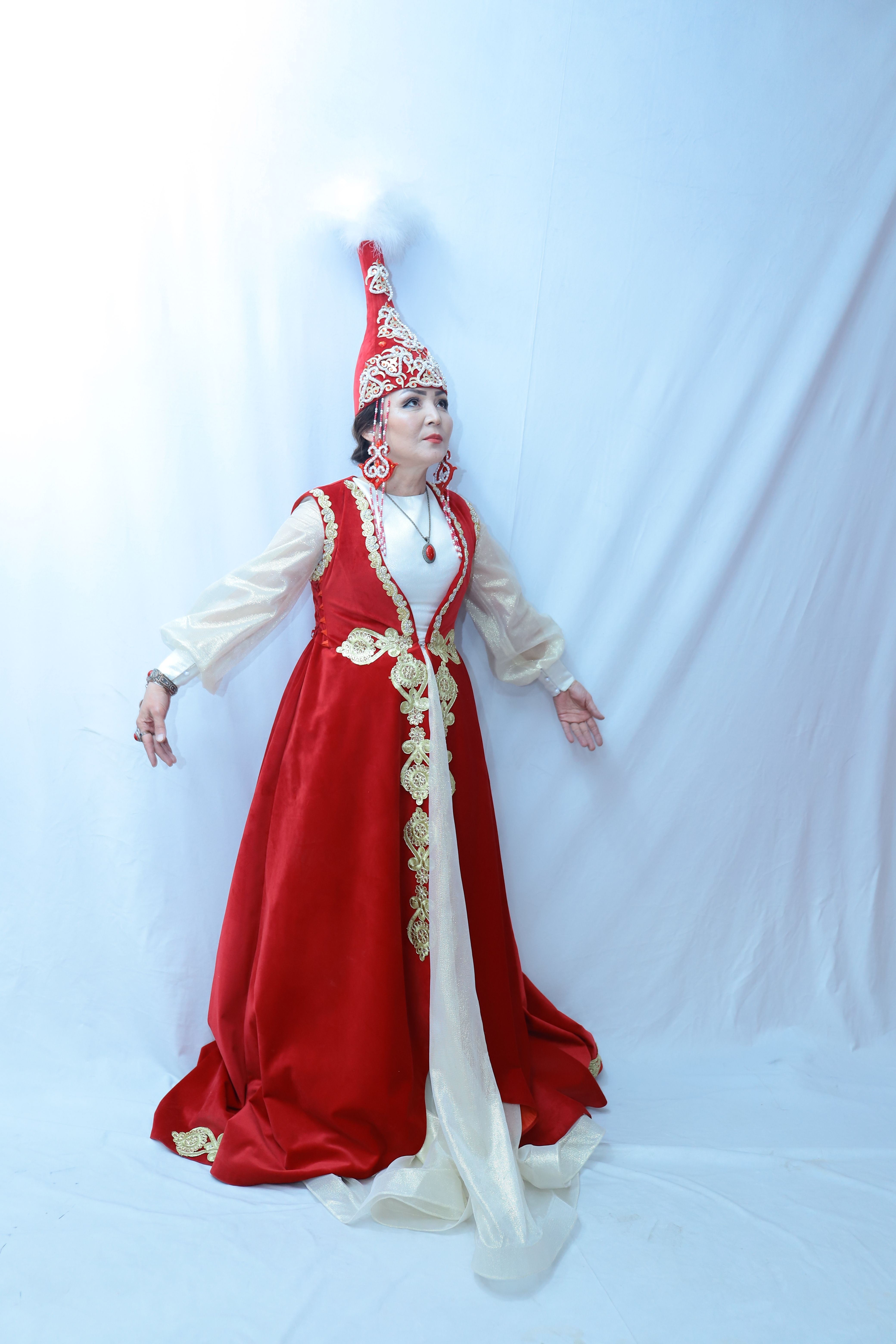 Woman in elaborate red and white traditional Asian attire with intricate details.