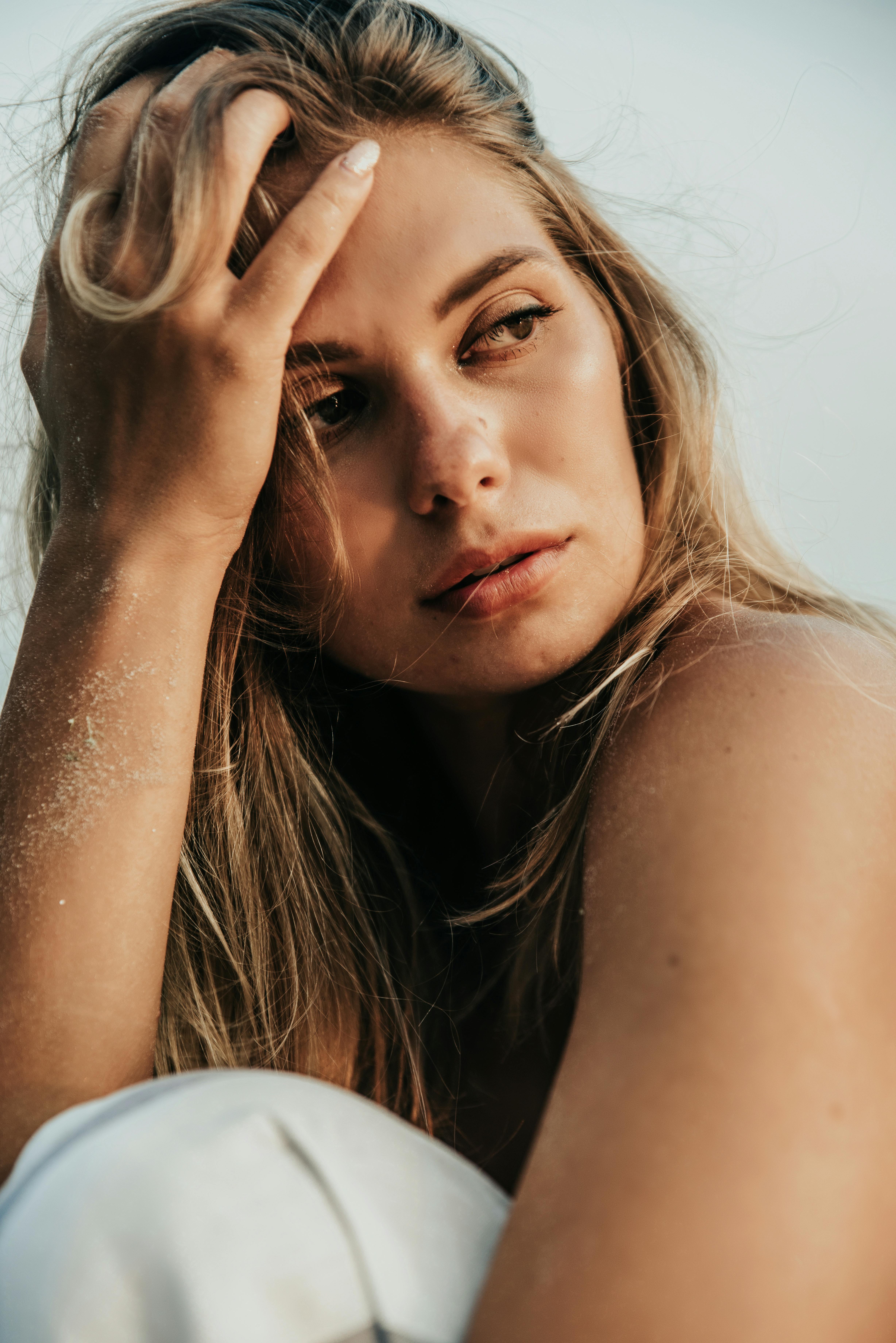 一位留着金色长发的女人的特写，在一个深思熟虑的时刻展示了优雅和美丽