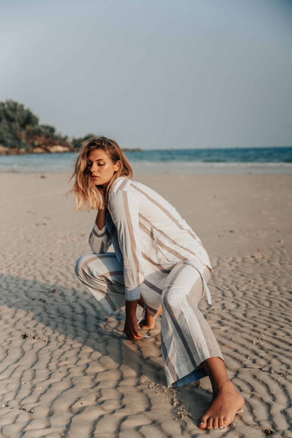 A woman posing on the beach in soft neutral stripes