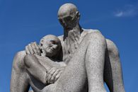 Stone sculpture of two elderly men in Vigeland Park, Oslo under clear skies.