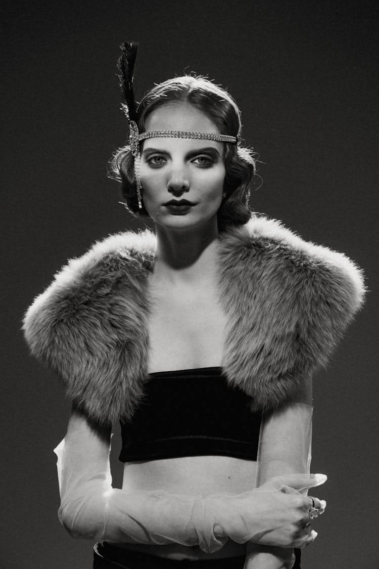 Grayscale Photo Of A Woman With Headband Wearing Black Tube Under A Fur Scarf