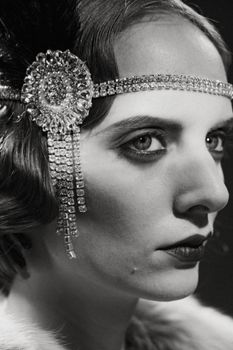 Elegant grayscale portrait of a woman in vintage flapper attire with a jeweled headband.