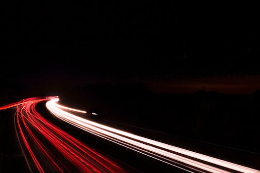 Captivating long exposure of car lights on a curving road at night, showcasing motion and vibrant colors.