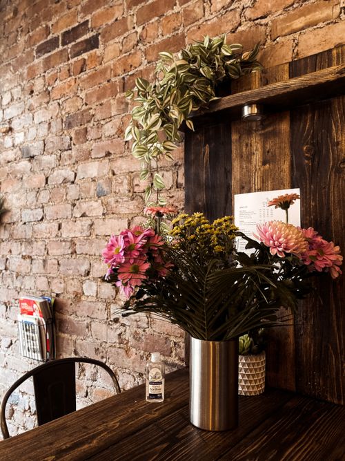 Free Bunch of fresh delicate flowers in vase placed on wooden table in elegant cafe with brick walls Stock Photo