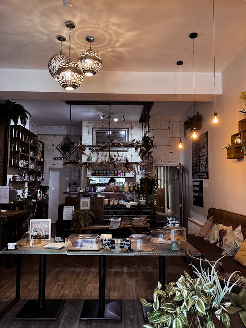 Interior of classic styled traditional cafe with elegant furniture and lamps and assorted baked products placed on tables