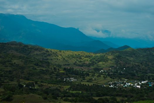 A breathtaking aerial view of a verdant valley and village amidst rolling hills in Kerala, India.
