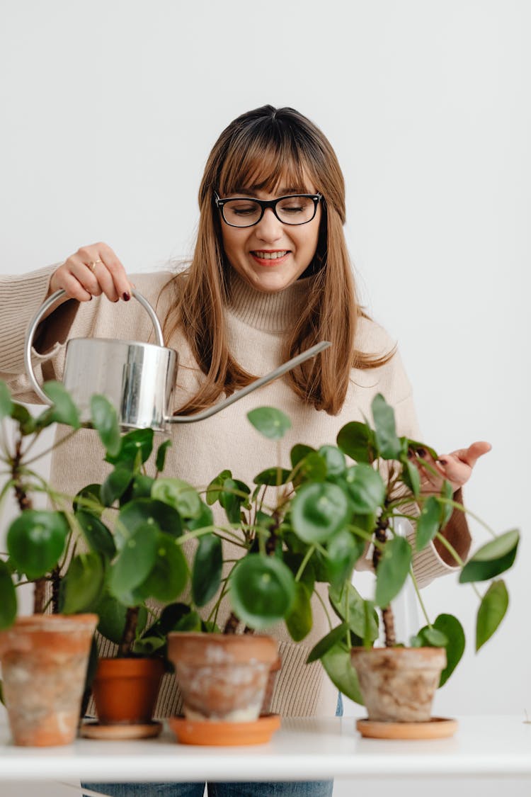 Smiling Woman Watering Plants In Pots