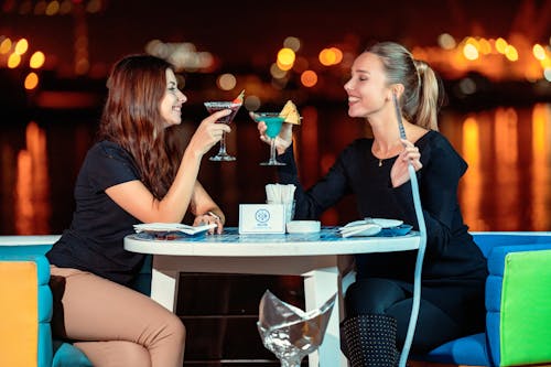 Free Women Sitting at the Table Holding Cocktail Glasses Stock Photo