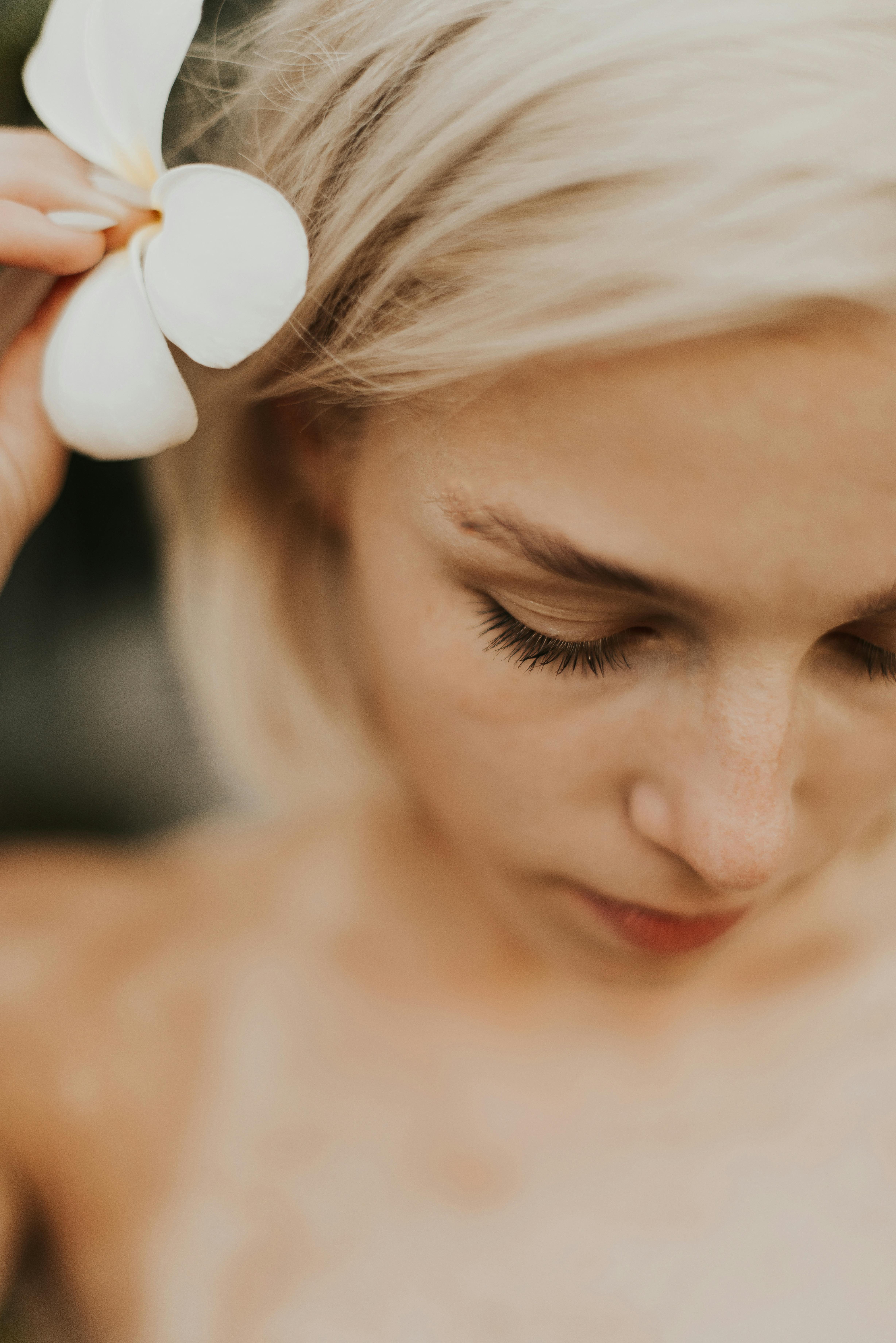 a woman putting a flower on her ear