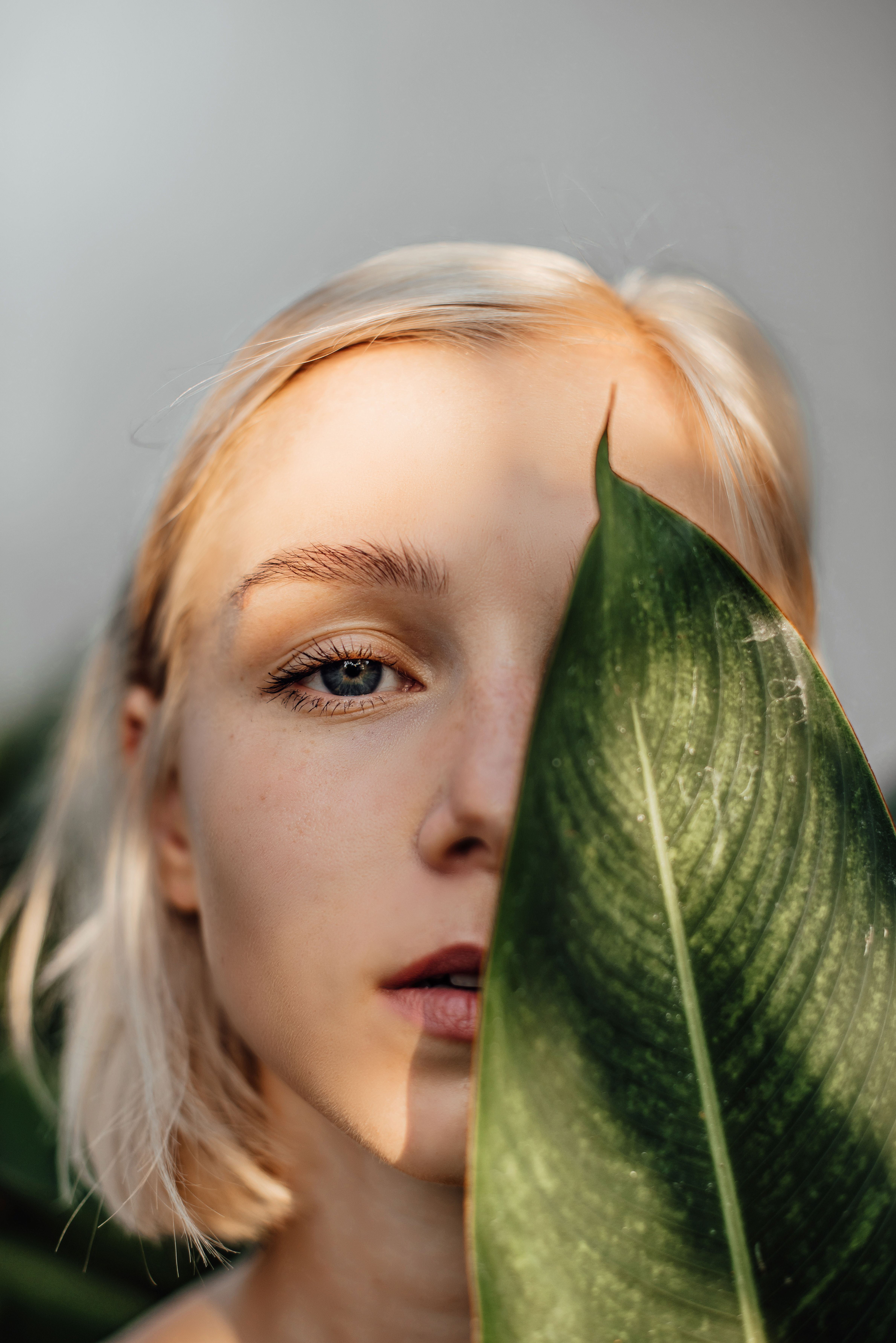 A Woman Covering Half of Her Face With a Leaf · Free Stock Photo