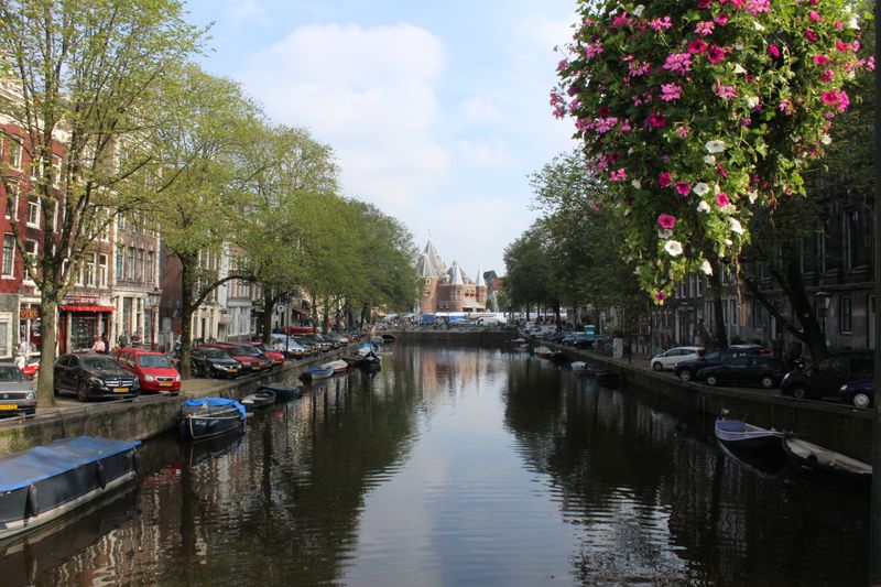 Beautiful Amsterdam canal view with flowers and historic architecture on a bright spring day.