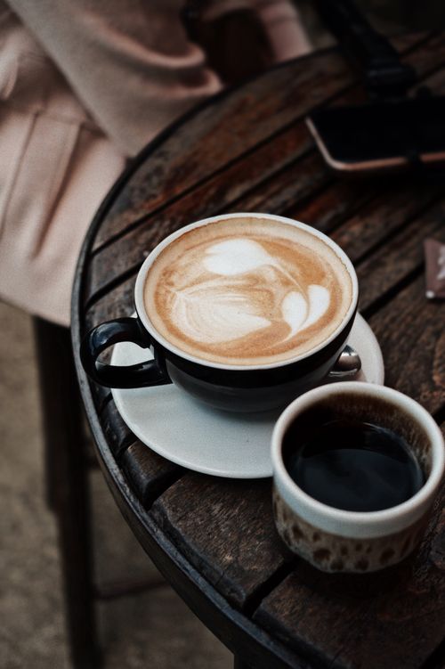 Free Artfully crafted latte and black coffee on rustic table, perfect for a cozy cafe ambiance. Stock Photo