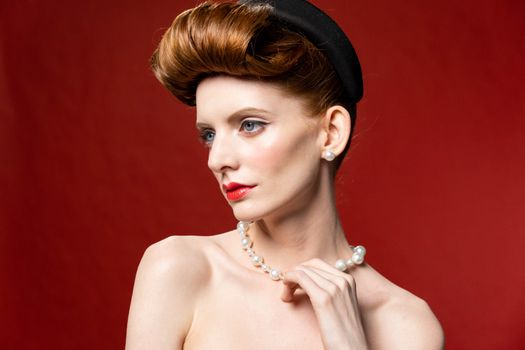 Vintage style portrait of a woman adorned with pearls against a red background, showcasing elegance and glamour.