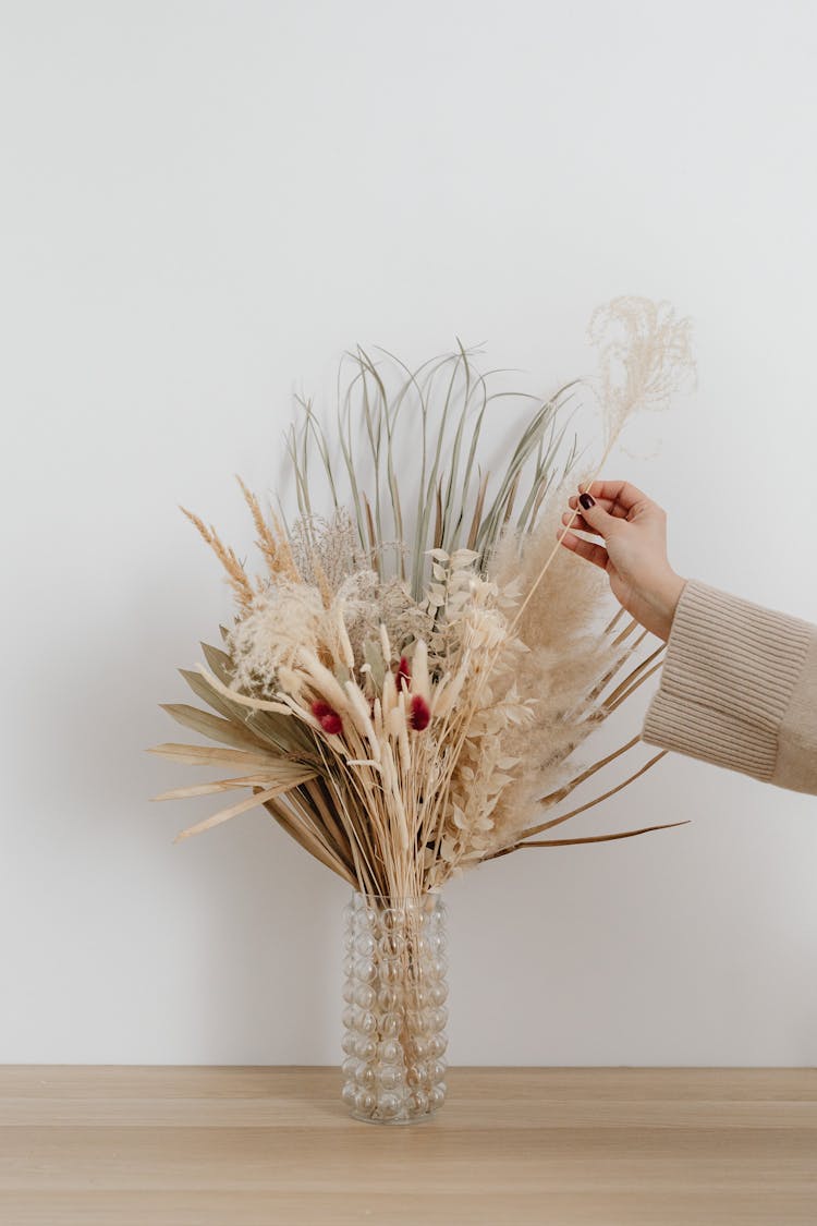 Person Making Dry Flowers Composition In Vase