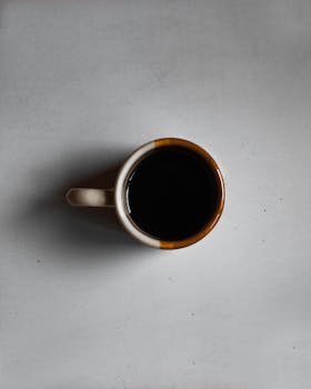 Aerial view of a ceramic mug filled with black coffee on a simple background.