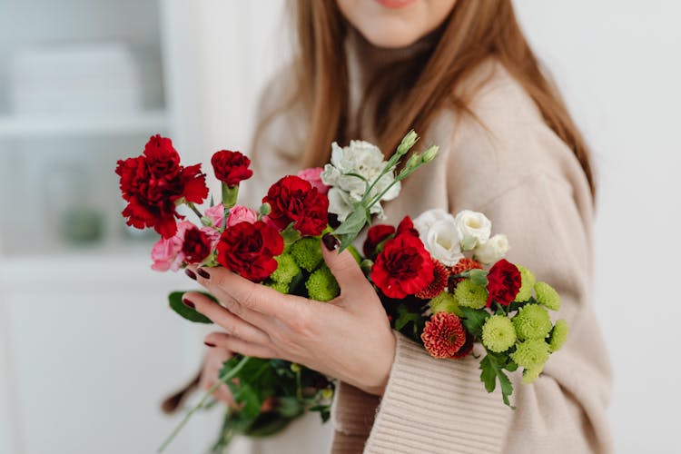 Woman In Beige Long Sleeves Holding A Bunch Of Flowers