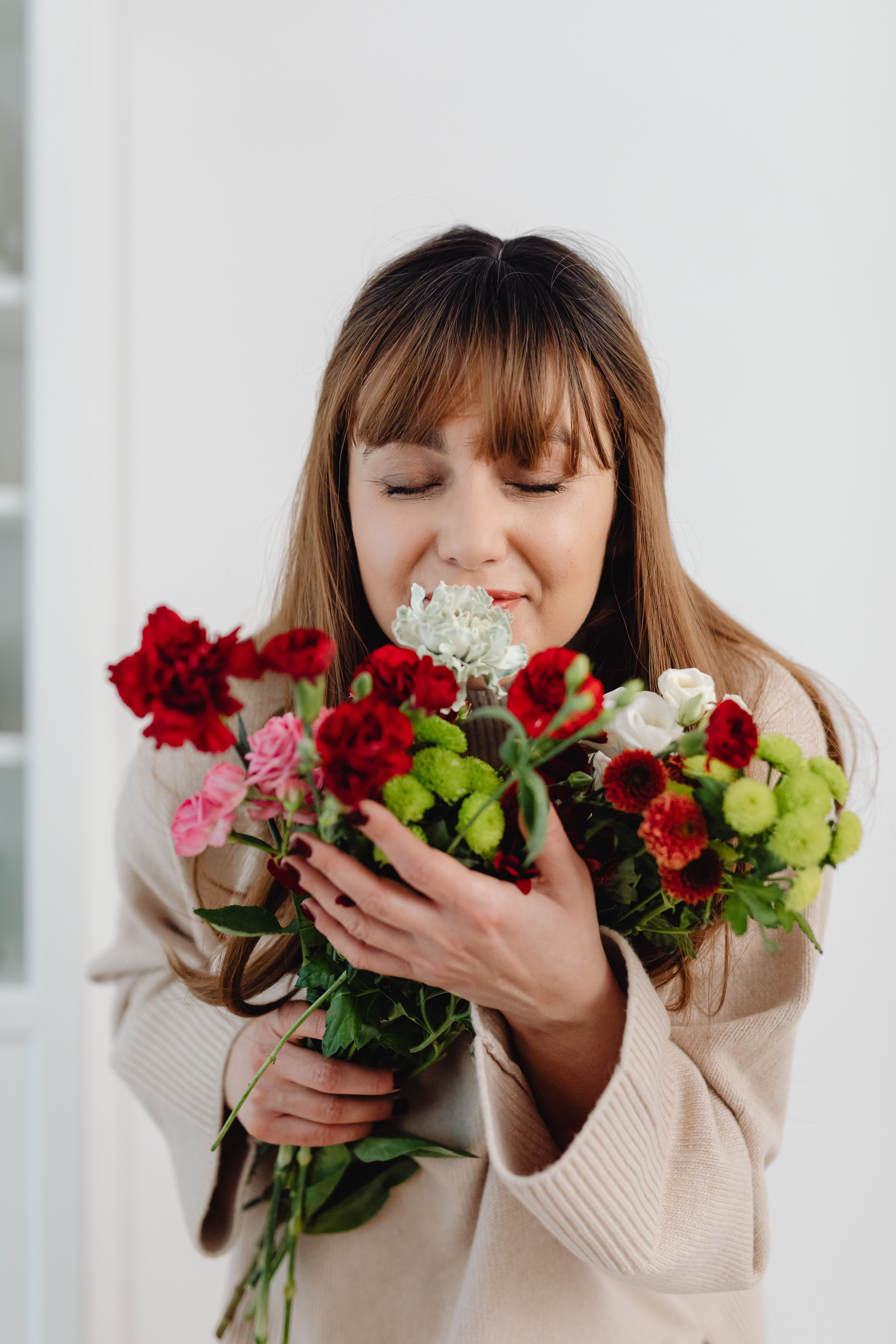 a-woman-smelling-a-bouquet-of-flowers-free-stock-photo