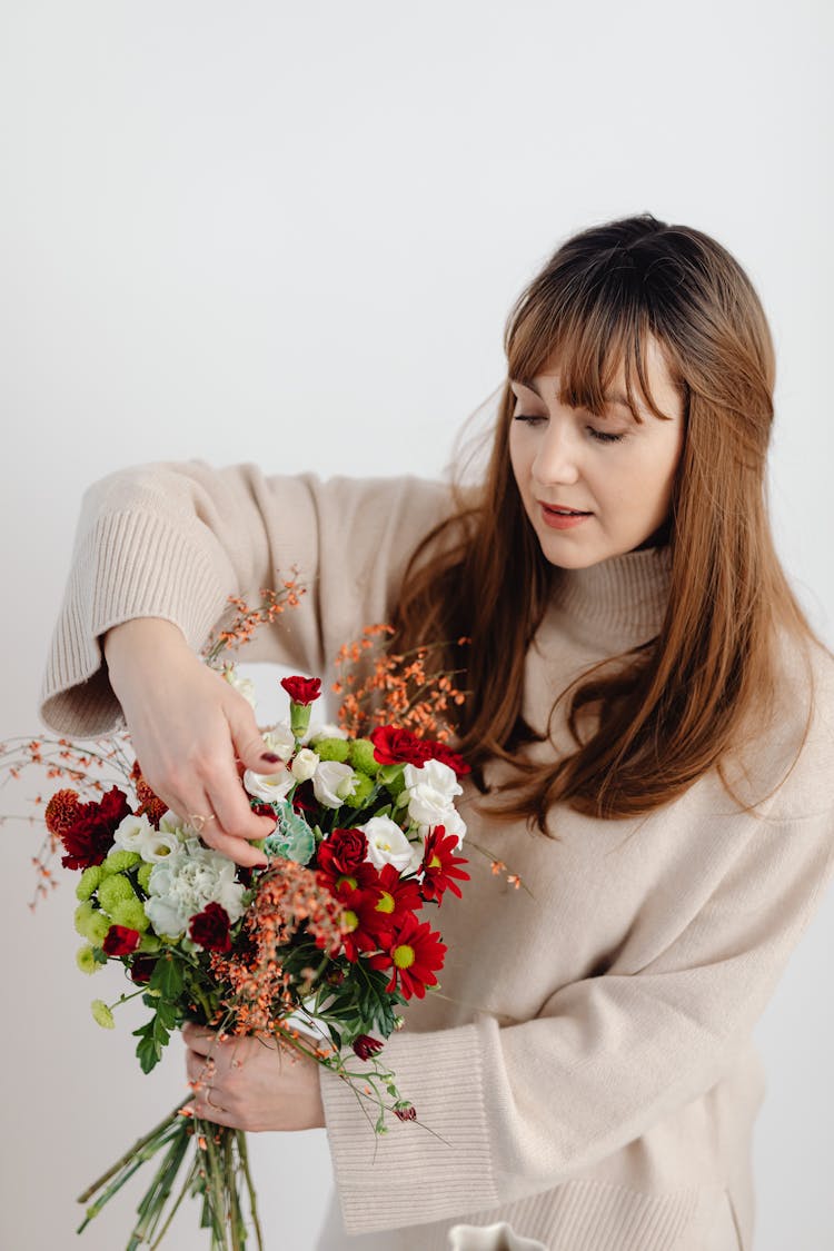 Beautiful Woman In Beige Sweater Holding A Bunch Of Flowers