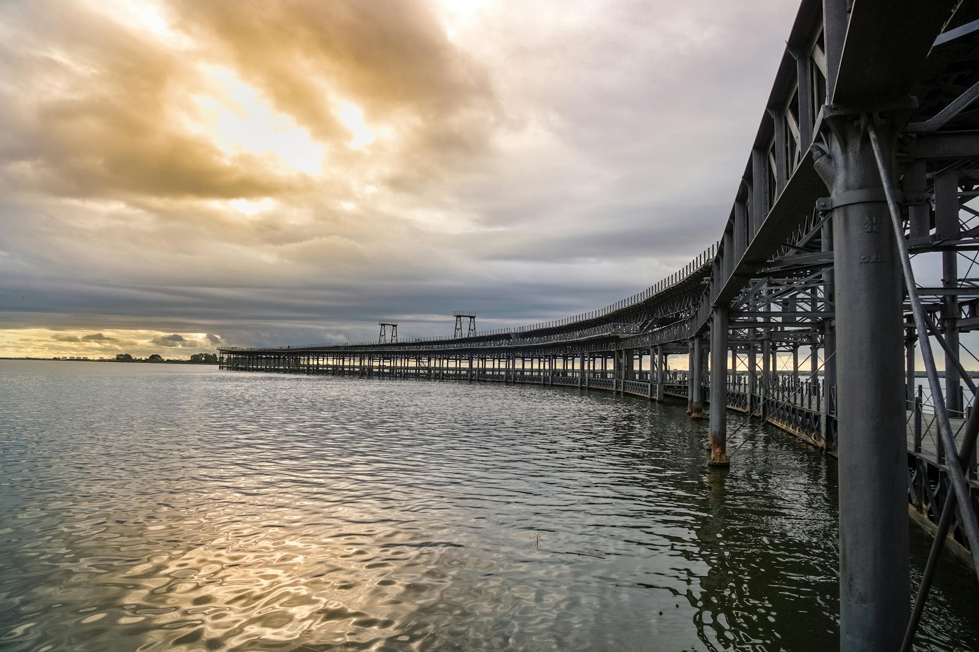 Scenic view of the Rio Tinto Pier at sunset reflecting in Huelva's calm waters.