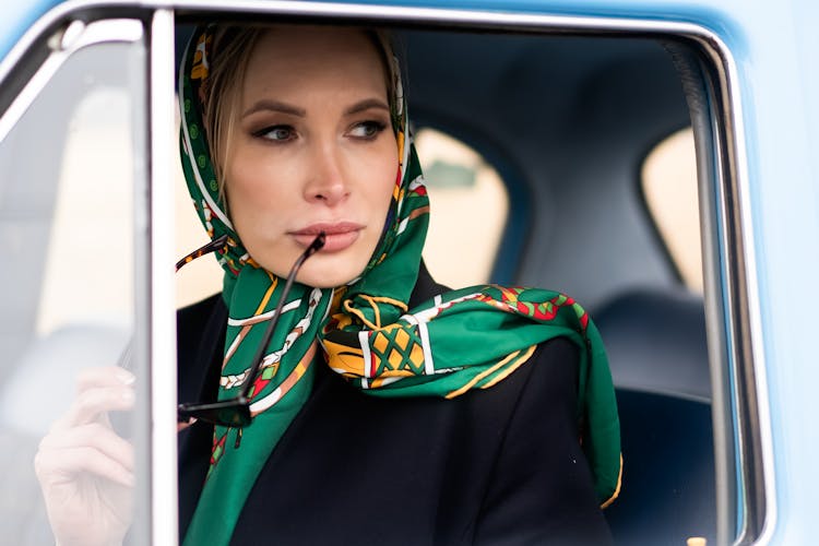 Pensive Female In Headscarf Driving Retro Car And Looking Away