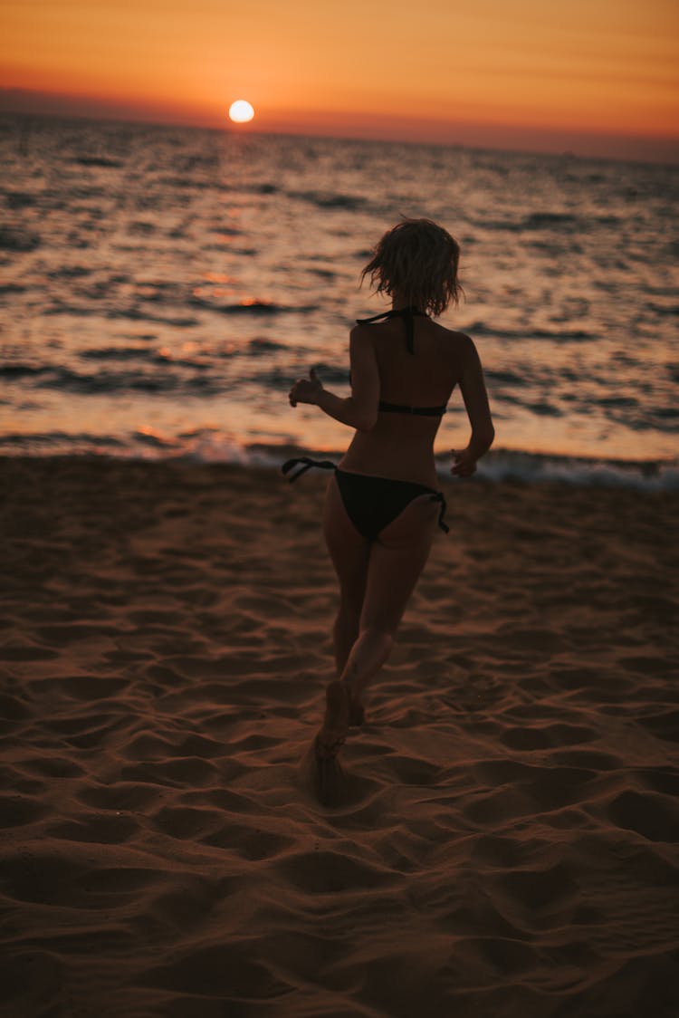 A Woman Running At The Beach During Sunset