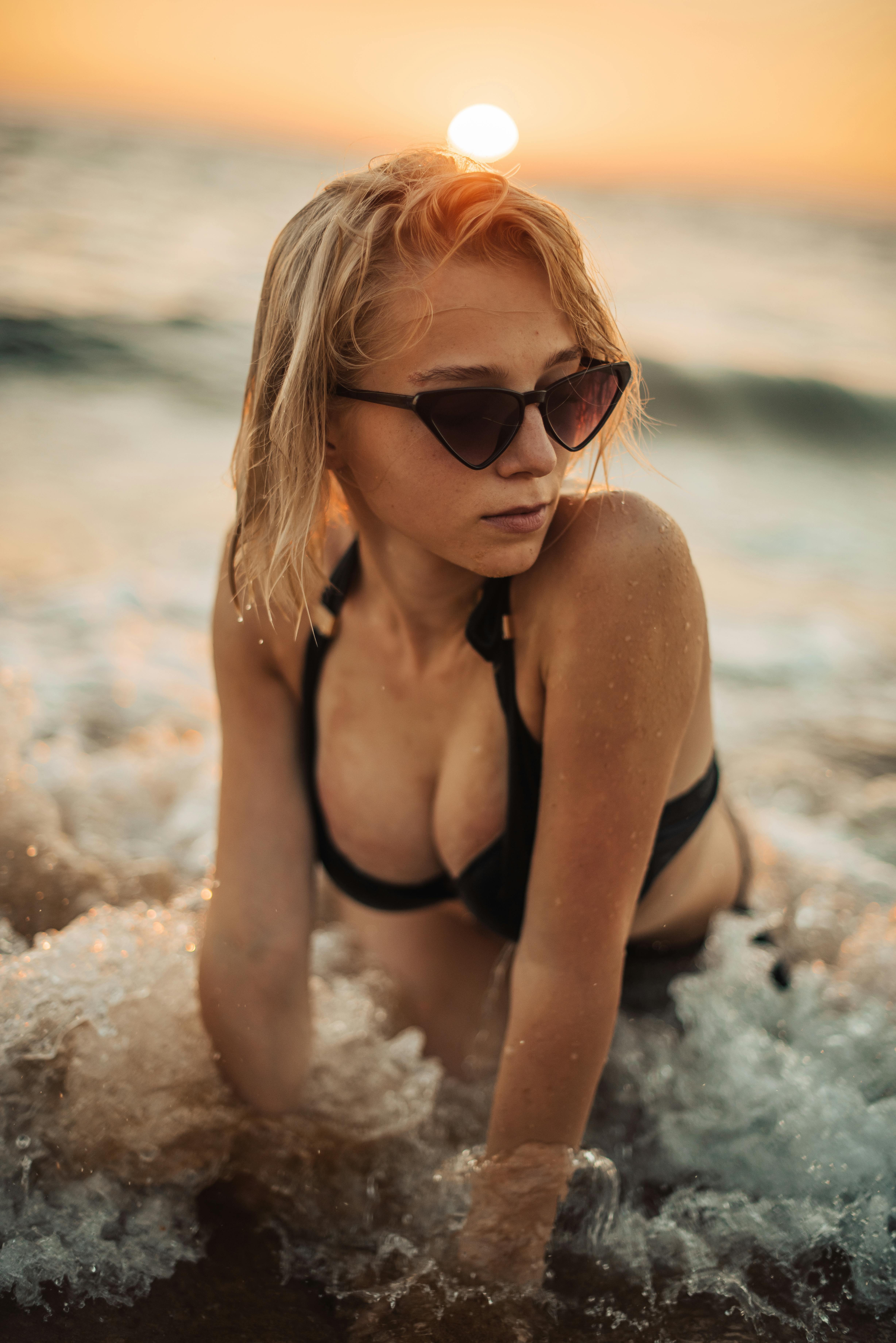 日落时分，一名年轻女子戴着墨镜，在海滩上冲浪