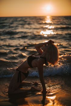 Silhouette of woman in bikini posing on a beach during sunset in Vietnam, capturing serene ocean waves.