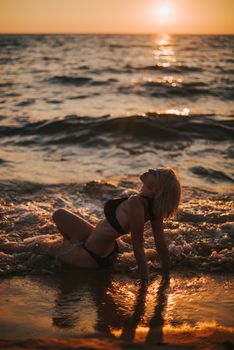 A woman in a bikini enjoying a sunset on a Vietnamese beach with waves crashing gently.