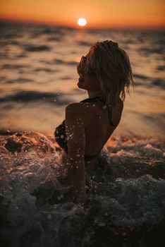 A woman enjoying the sunset waves at a Vietnamese beach, capturing the golden hour's beauty.