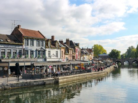 Picturesque view of Amiens, France with vibrant buildings along a calm canal, showcasing a serene town atmosphere.