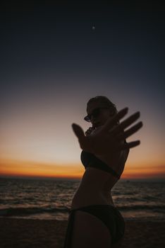 A captivating silhouette of a woman posing on a beach at sunset, capturing tranquil ocean vibes.