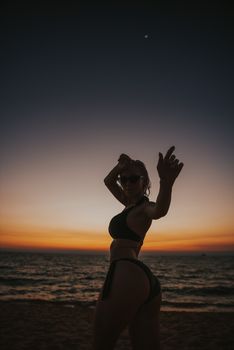 Silhouette of a woman in a bikini posing by the ocean during a stunning Vietnam sunset.