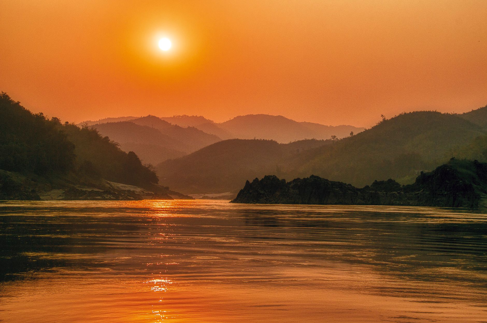 Serene sunset landscape over the Mekong River with scenic mountains in Bokeo Province, Laos.
