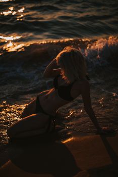 A serene portrait of a woman in a silhouette as the sun sets over the ocean waves.